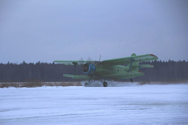 Разбрызгивая снег и воду, Ан-2 идет на взлет.