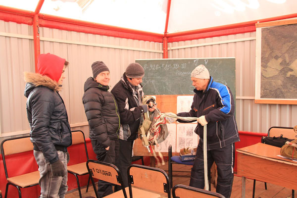 Наиболее опытный парашютист Андрей Штермер (второй справа)
показывает новичкам как собирать парашютные стропы в
бесконечную петлю после приземления.